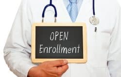 doctor holding a sign that says open enrollment california