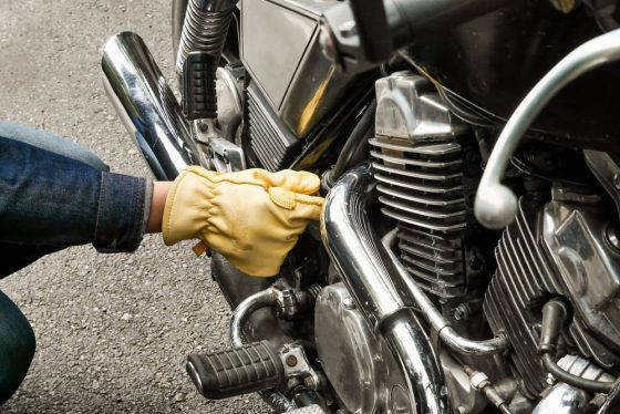 man with glove checking motorcycle for maintance checklist