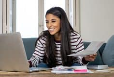 young hispanic woman filing taxes online on laptop