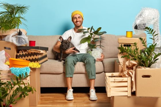 young man in hist first rental apartment with boxes and dog