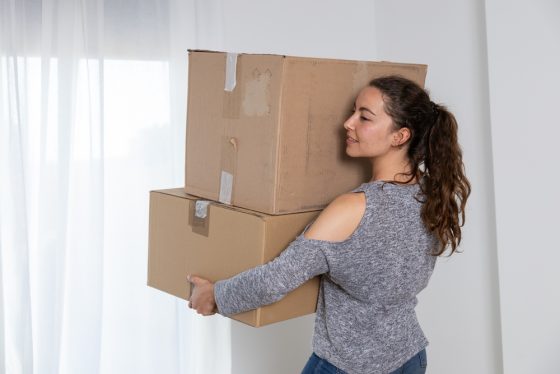 A woman carrying moving boxes inside her new apartment, preparing to settle in with the protection of renters insurance.