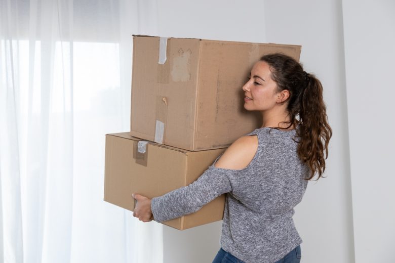 A woman carrying moving boxes inside her new apartment, preparing to settle in with the protection of renters insurance.