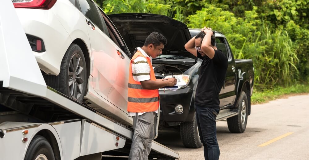 A frustrated driver speaks with a tow truck operator while their vehicle is loaded, representing what to do after a car towed in California.