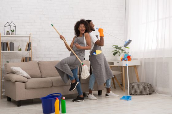 African American couple dances with cleaning tools in their living room