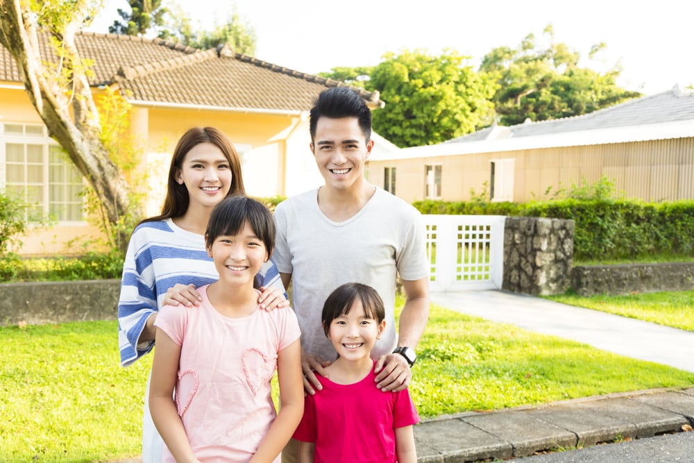 Young Asian family stands in their front yard