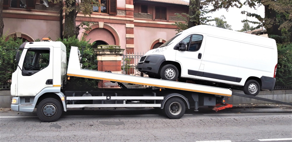 A tow truck loads a broken delivery van