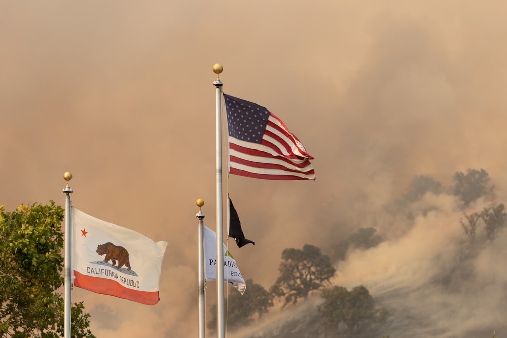 American and California flags wave in the smoke from a wildfire