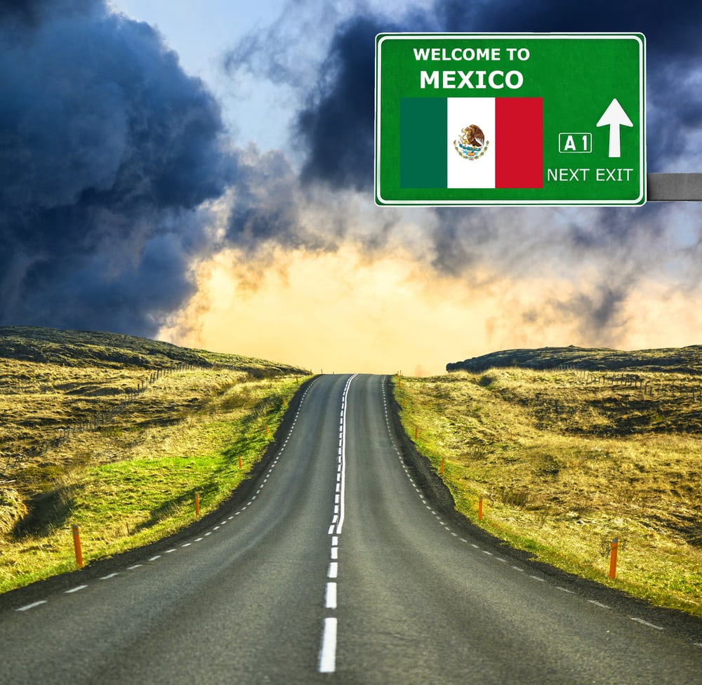 desolate road with storm clouds and sign welcome to mexico