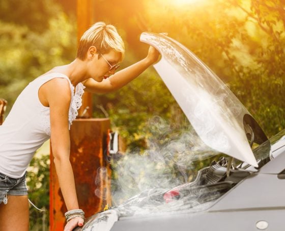 Young woman with car hood raised and steam coming from engine