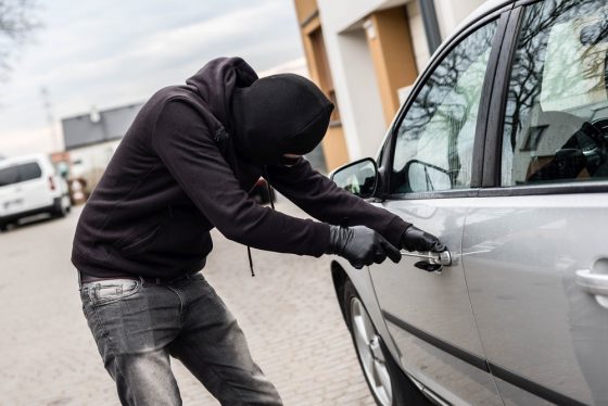 Thief in black attempting to steal a new car