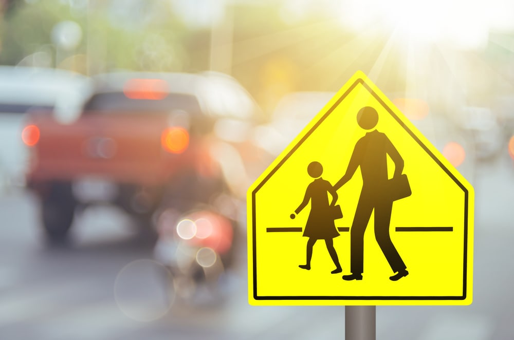 Image of a school zone sign with a blurred background showing a red truck