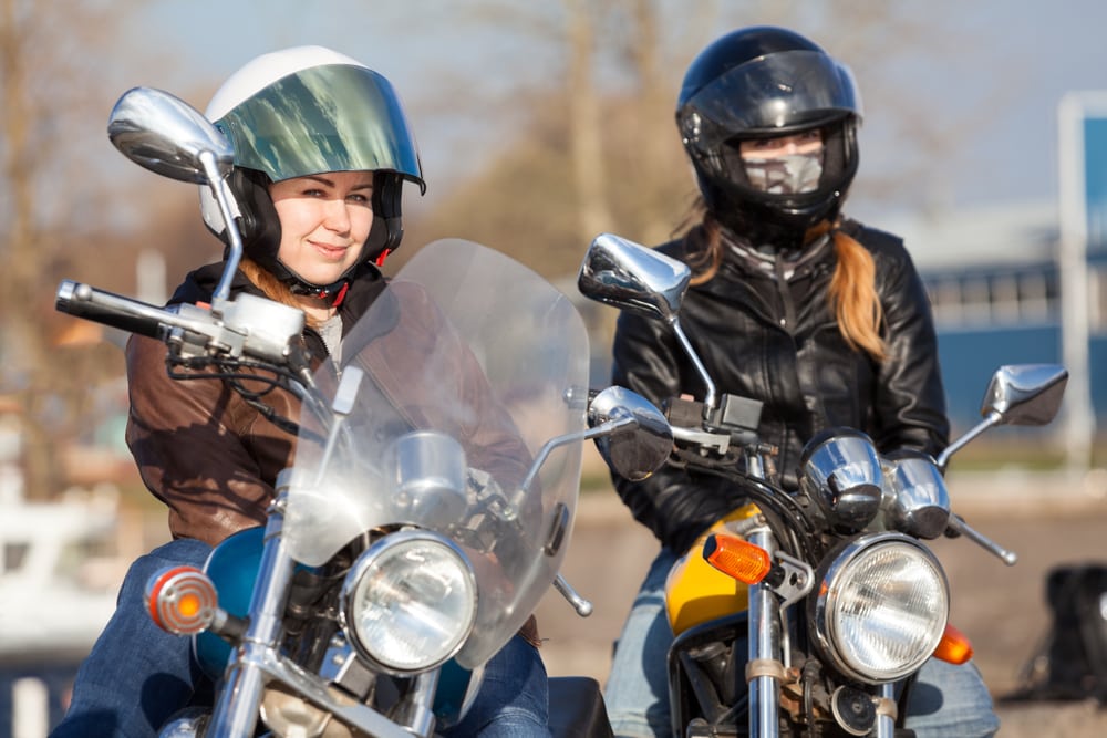 Two female motorcyclists looking at the camera.