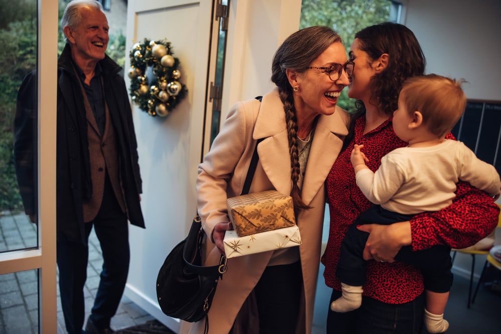 Grandparents arrive for a holiday visit with mom holding baby at the door - homeowners insurance in California