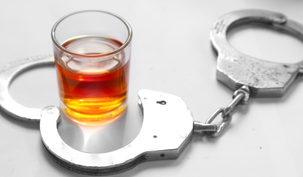 Glass of whiskey, handcuffs, driving while intoxicated concept - cheap SR-22 insurance in California