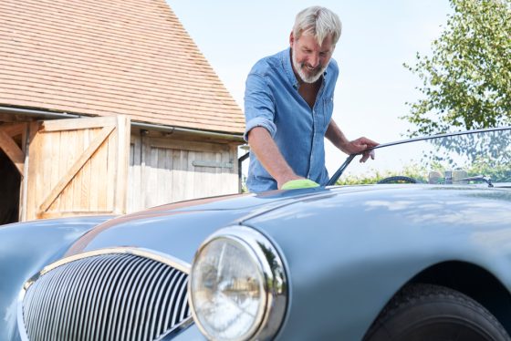 Senior man lovingly polishes his classic car - cheap classic car insurance in California