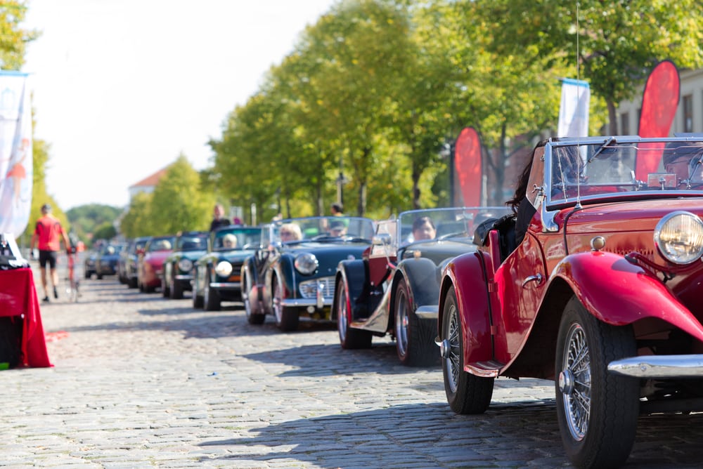 A line of classic cars in a show - cheap classic car insurance in California