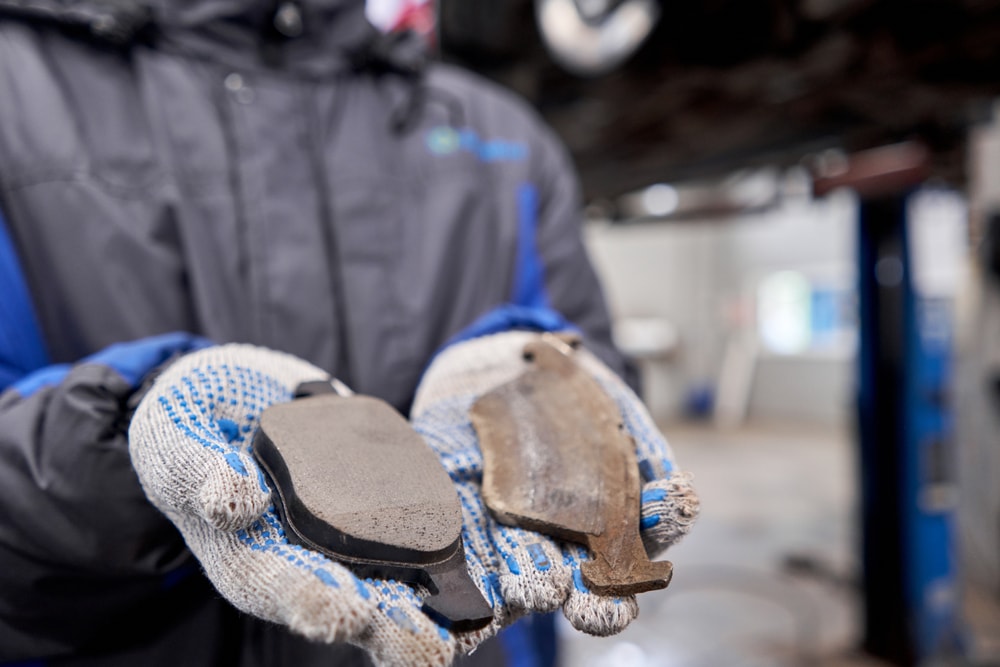 Hands holding a comparison old brake pads with new brake pads.