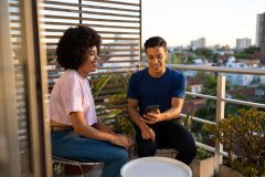 Two friends sitting on an apartment balcony - cheap renters insurance in California.