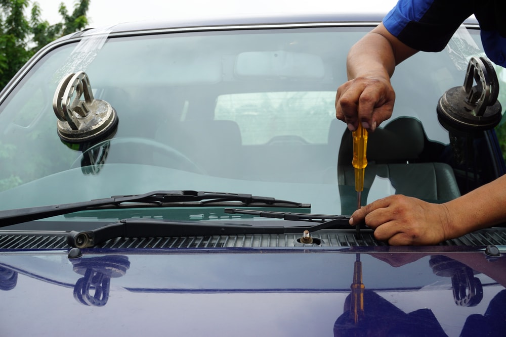 Technician hands replacing or repairing a cracked windshield.