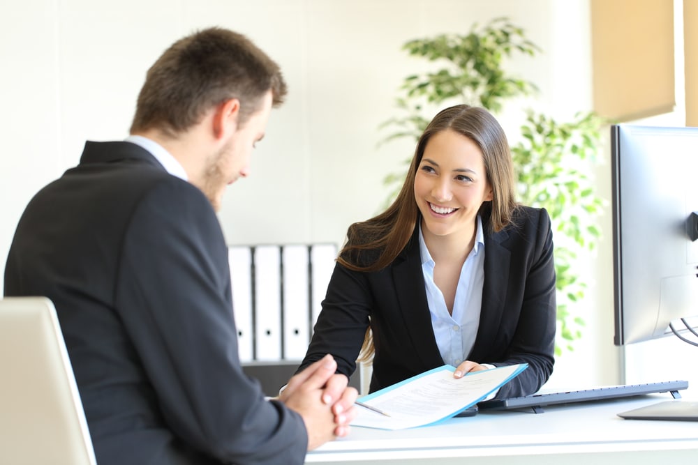 Smiling female insurance agent helps customer find a way to lower his insurance bill in California.