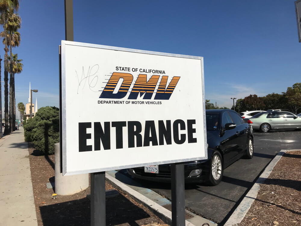 California DMV entrance sign outside a parking lot, illustrating how to get in and out of the DMV fast in california.