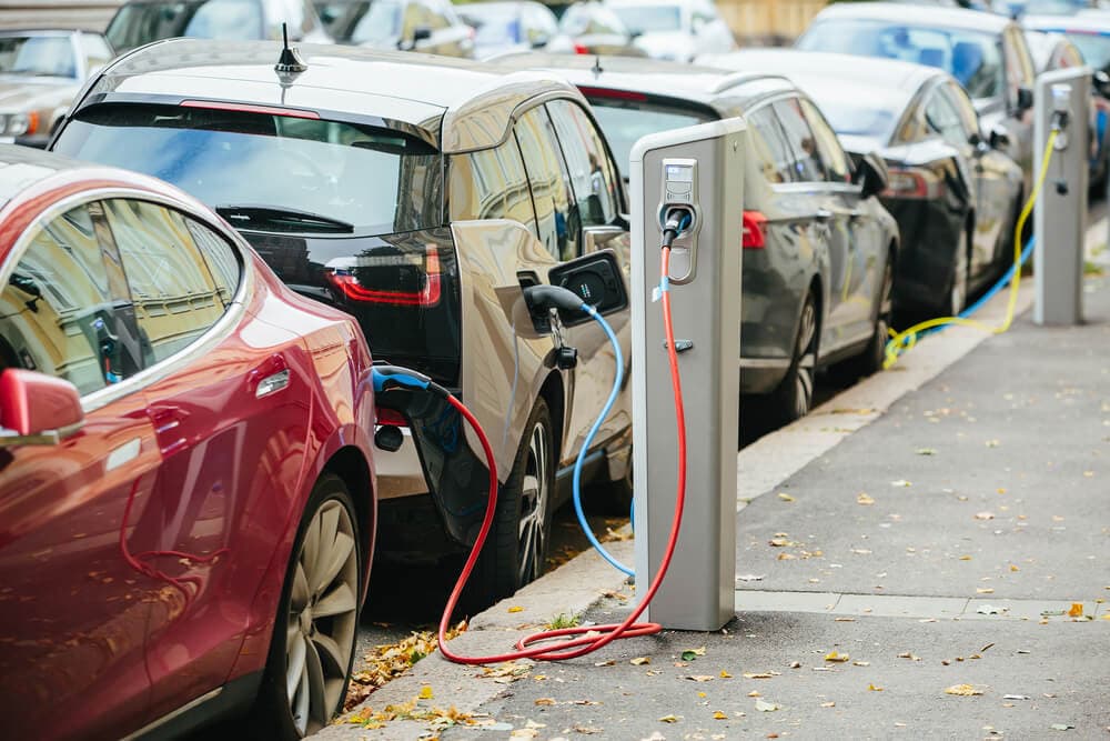 Electric cars lined up to charge at charging stations on the street.