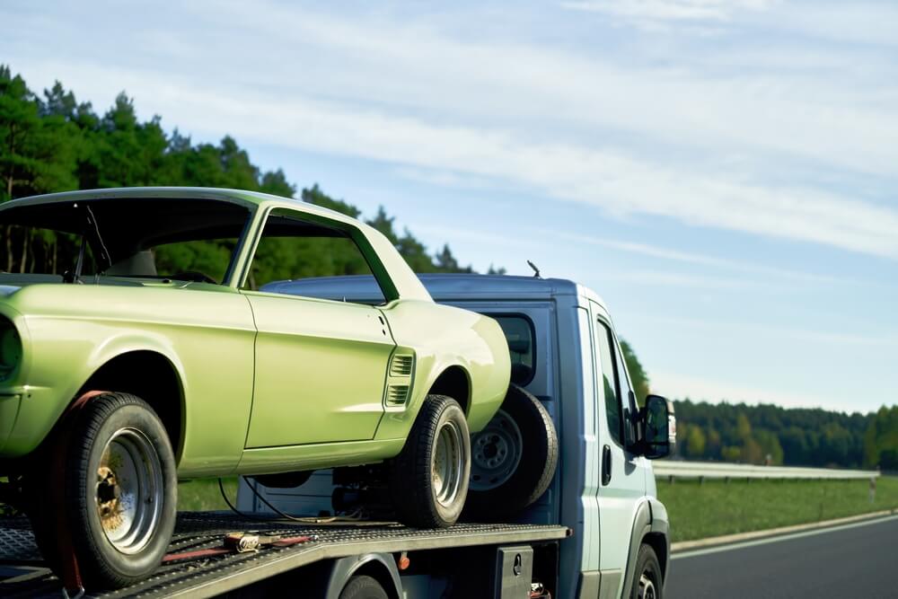 Classic green muscle car being transported on a trailer, illustrating classic car insurance California protection for vehicle transport and storage.