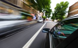 Image of speeding car on street as lights whizz by - cheap car insurance in California.