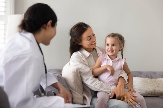 Mother holding her young daughter during a pediatric visit, illustrating the importance of kids life insurance for protecting a child’s future.