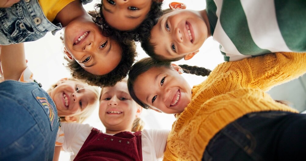 Group of smiling children looking down at the camera, representing the value of kids life insurance for securing financial protection for families.