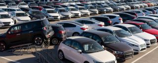 Large parking lot filled with rows of new cars in various makes, models, and colors, illustrating a broad selection of vehicles available for purchase.