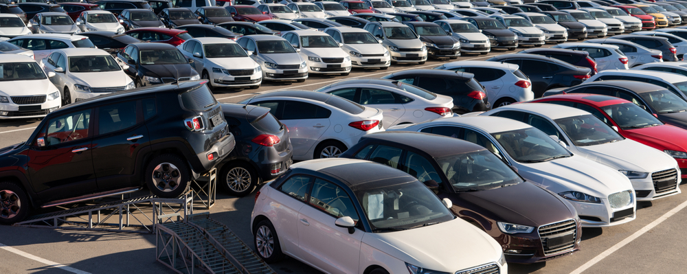 Large parking lot filled with rows of new cars in various makes, models, and colors, illustrating a broad selection of vehicles available for purchase.