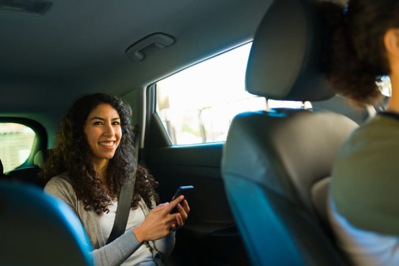 Woman rideshare passenger smiles from the back seat of her rideshare vehicle - cheap rideshare insurance in California.