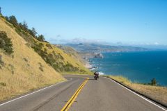 Motorcyclist drives along coastal road in California with the ocean on the right - cheap motorcycle insurance.