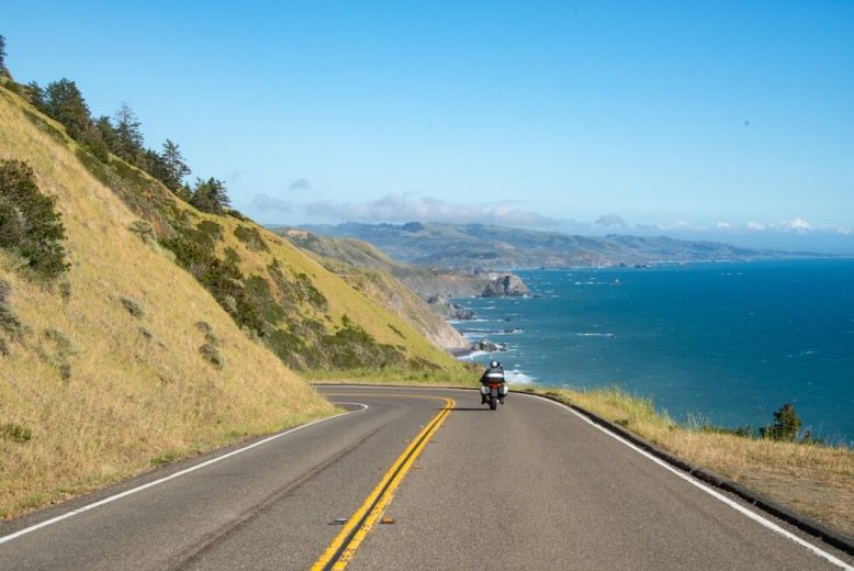Motorcyclist drives along coastal road in California with the ocean on the right - cheap motorcycle insurance.
