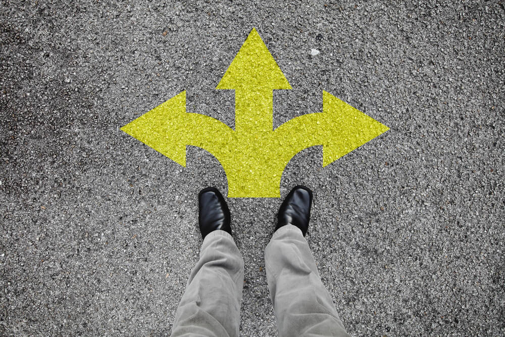 Feet on a pavement with three directional sign - cheapest car insurance in California.
