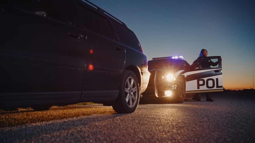 A police officer gets out of her car to approach a driver's vehicle - cheap car insurance in California.