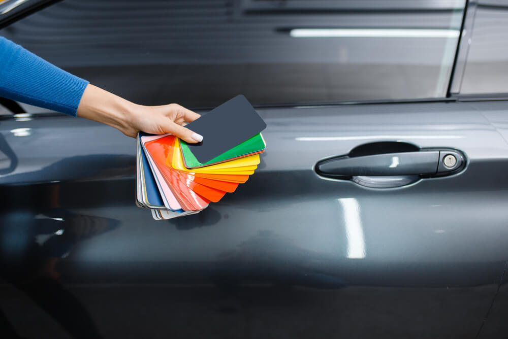 Car wrapping, hand with foil or film color palette, making car modifications and the effect on car insurance.