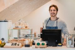 Waiter standing at cafe counter in small cafeteria that has Health Insurance Options for Self-Employed Californians