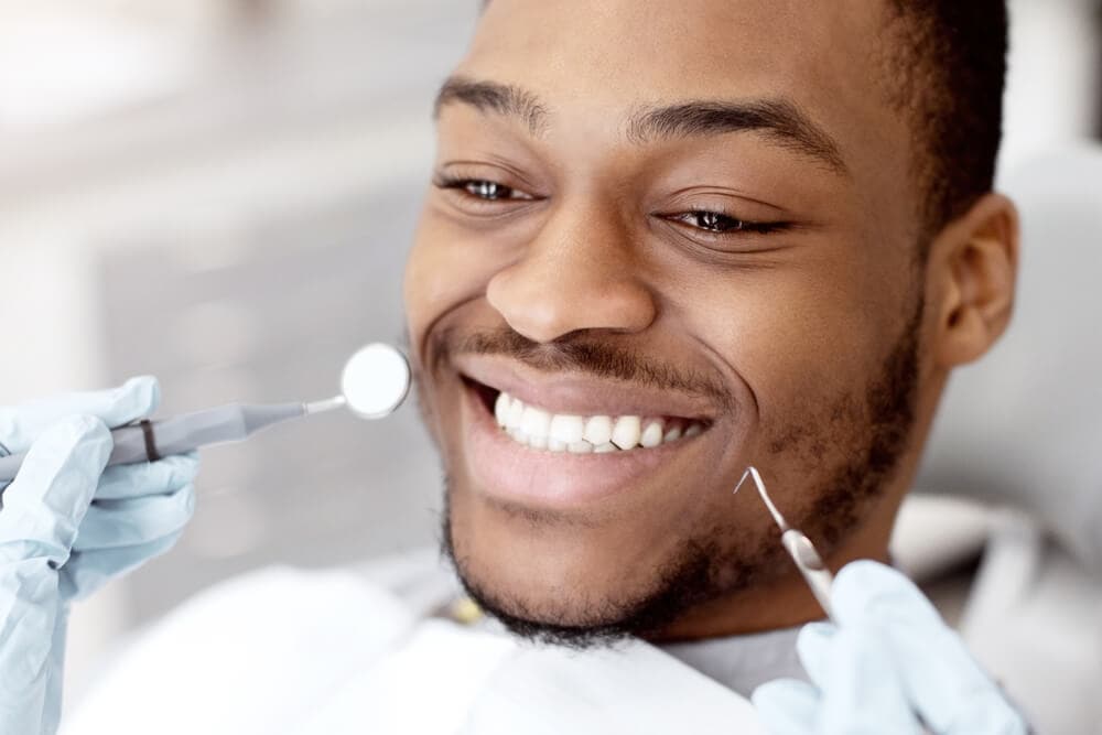 Portrait Of Young Black Male Patient Sitting in Chair in Dental Clinic.