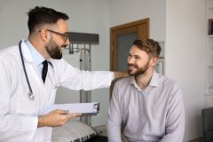 Doctor speaks with a patient during a healthcare visit about insurance coverage and Open Enrollment.