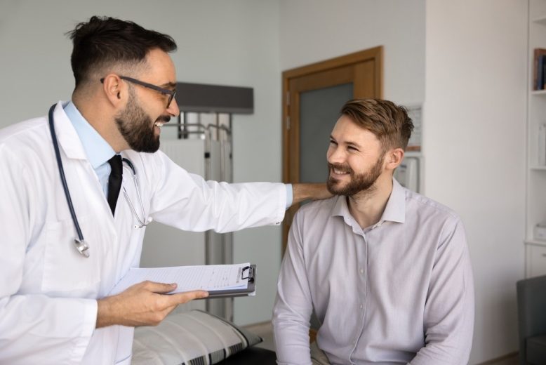 Doctor speaks with a patient during a healthcare visit about insurance coverage and Open Enrollment.