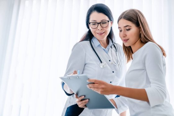 Doctor reviewing medical information on a clipboard with a young woman during a consultation, illustrating access to care through health insurance for part time workers in california.