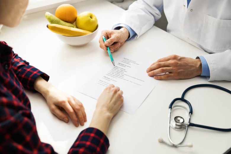 A healthcare provider explains treatment details on a tablet to a seated patient, illustrating how bronze silver gold platinum health plans California support different levels of care and affordability.