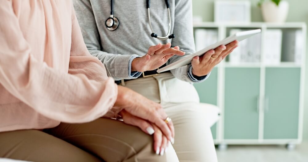 A doctor and patient sit at a desk reviewing a medical form together, reflecting how bronze silver gold platinum health plans California help individuals compare coverage options and make informed healthcare decisions.