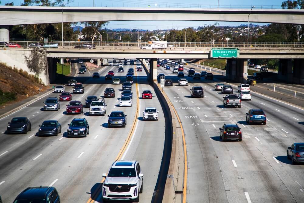 Cars moving along a busy California freeway under an overpass, illustrating everyday driving conditions after drivers reinstate car insurance in California.