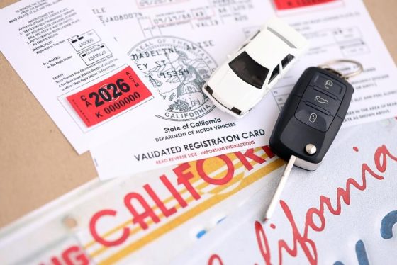 California vehicle registration card, license plate, and car key displayed together, representing requirements for car insurance out of state plates California.