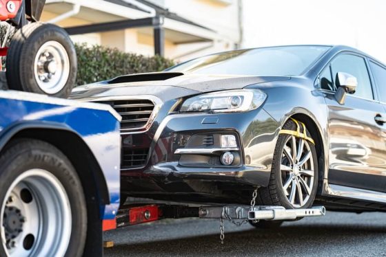 Car being loaded onto a tow truck, illustrating car towing in California and how car insurance may cover towing services.