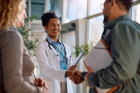 Doctor greeting patients during a visit, representing how a covered california income change can affect healthcare coverage eligibility.