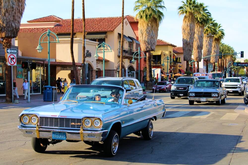 Classic convertible cruising down a palm-lined California street, illustrating why drivers should Update Car Insurance After Moving California.